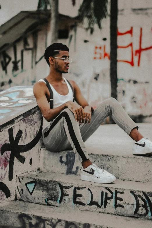 a man wearing glasses and vest sits on a wall