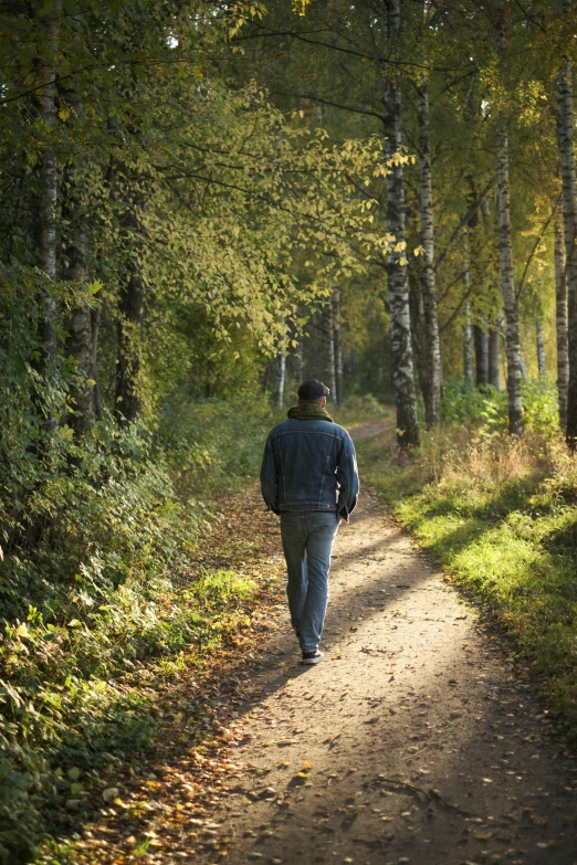 a man walking down a dirt road on the woods