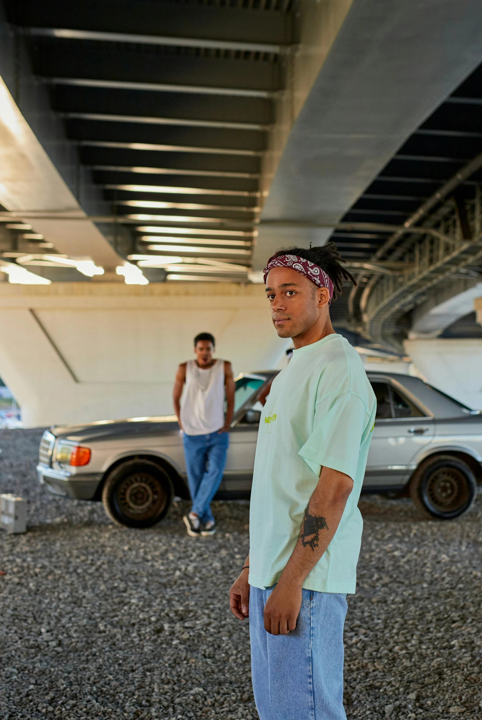 two men standing next to each other under a bridge