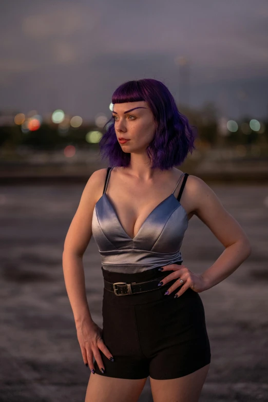 a woman with purple hair poses wearing black and silver clothing