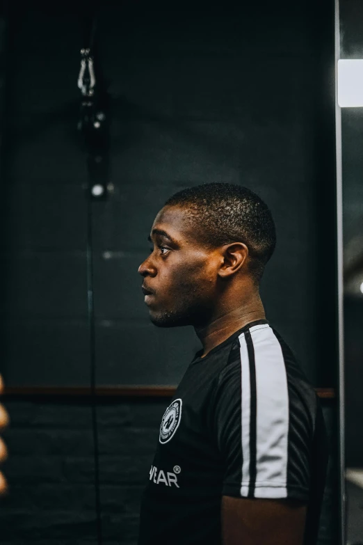 a black man in black and white shirt standing in front of mirror