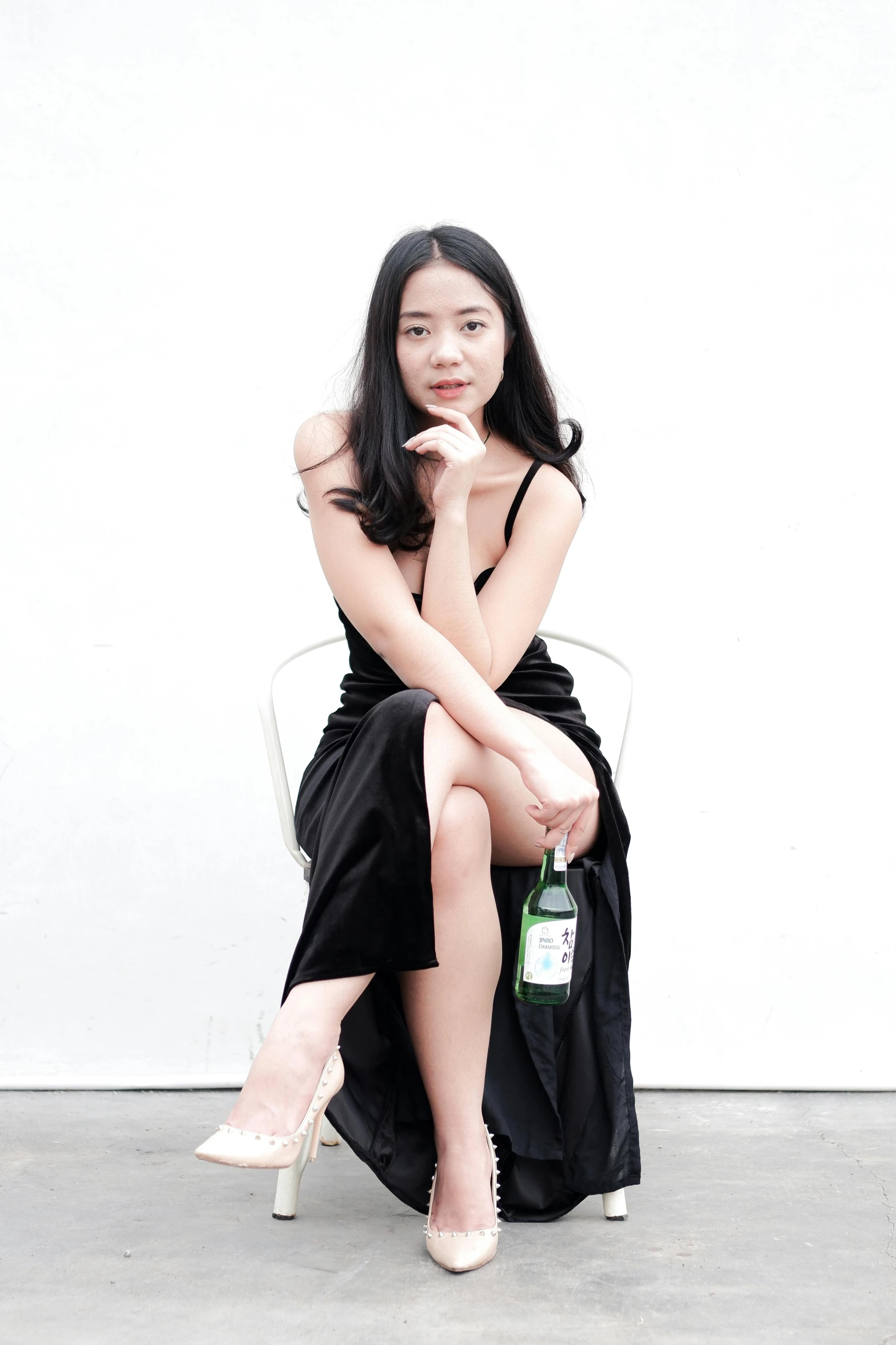 woman in black dress sitting on chair, smiling at camera