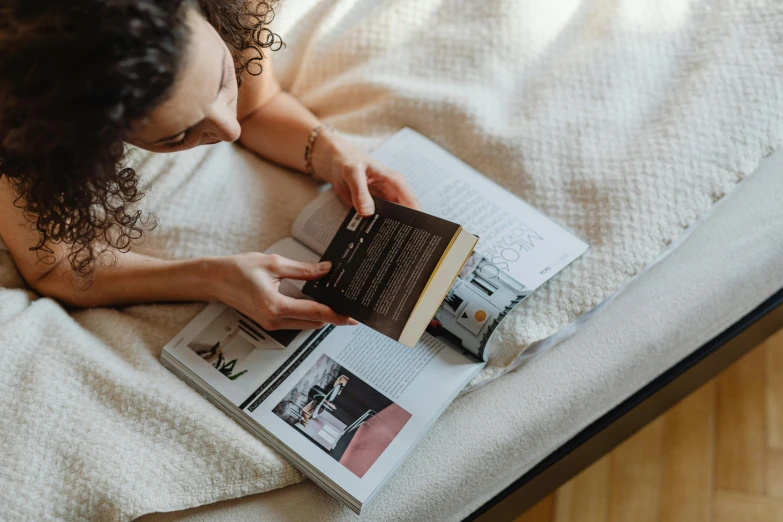 a woman is reading a book on a bed