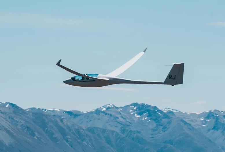 a small plane in the sky flying over a mountain range