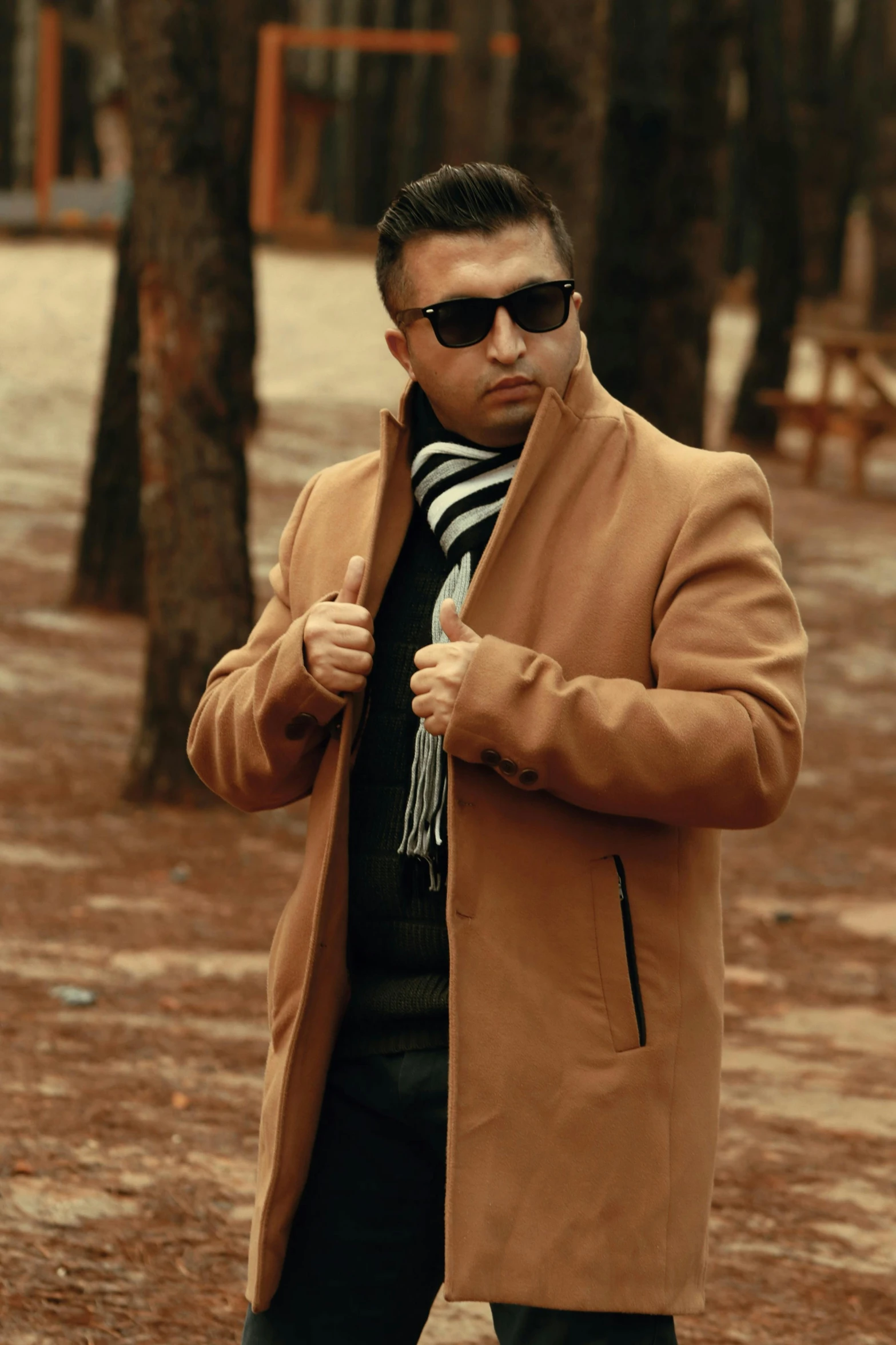 a man is walking in a park wearing a coat