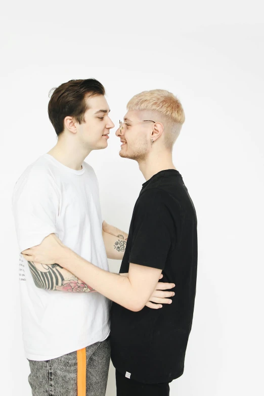 two young men in t - shirts are smiling and one of them has a goatee on his ear