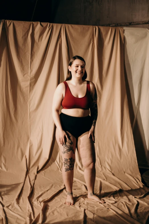 a woman with very small tattoos standing in a brown backdrop