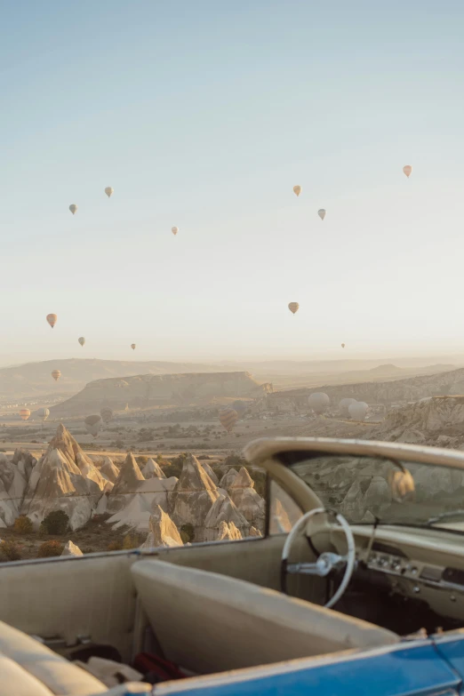 a view from a vehicle of  air balloons over a valley