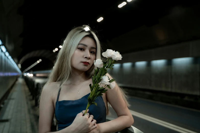 the  is standing at a train station with a flower