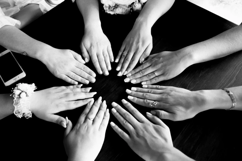 four hands joining the middle of a circle on top of a table