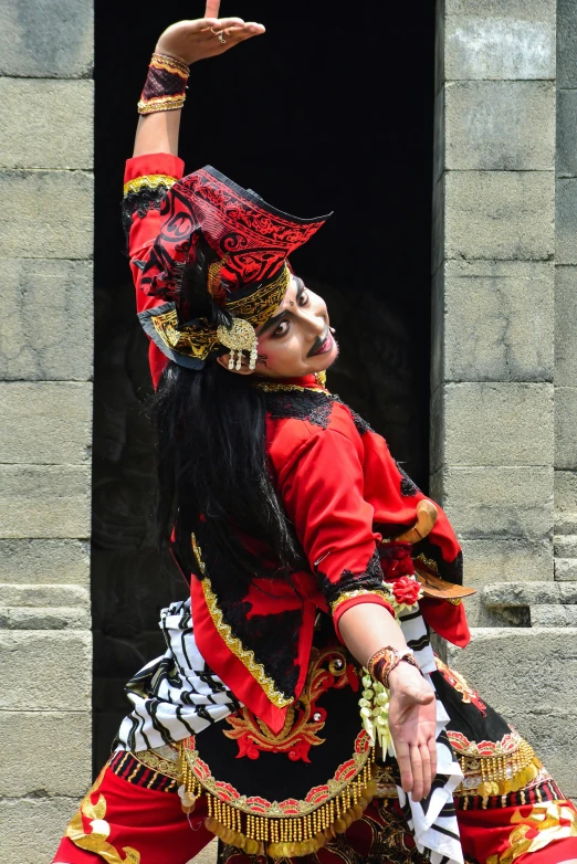 a woman is dressed in red and gold while dancing