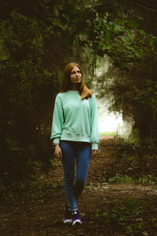 a woman walks through the forest with trees in the background