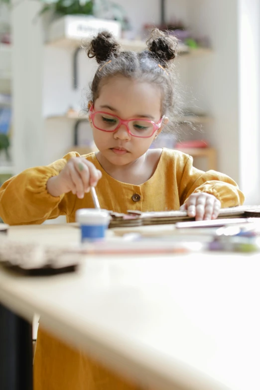 a girl wearing pink glasses doing soing on top of a white table