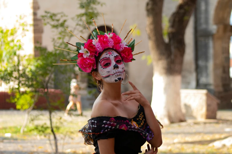 an attractive woman in skull makeup and pink flowers on her head