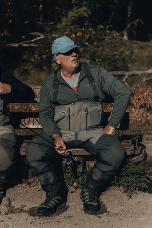 a man wearing snow gear sitting on a bench with another person