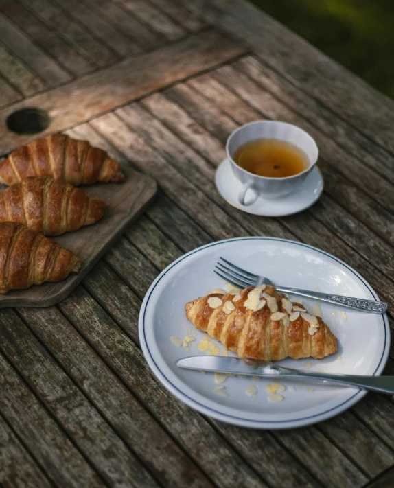 some plates and cups with croissants on a table