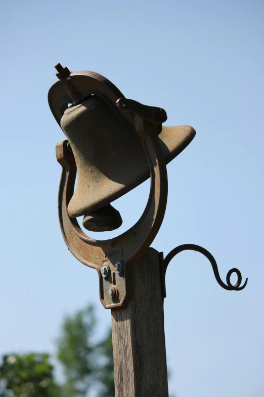 an old rusty bell hangs on an iron post