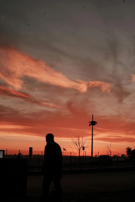 a man stands at the corner as the sun sets