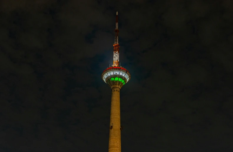 a very tall tower with a green light at the top