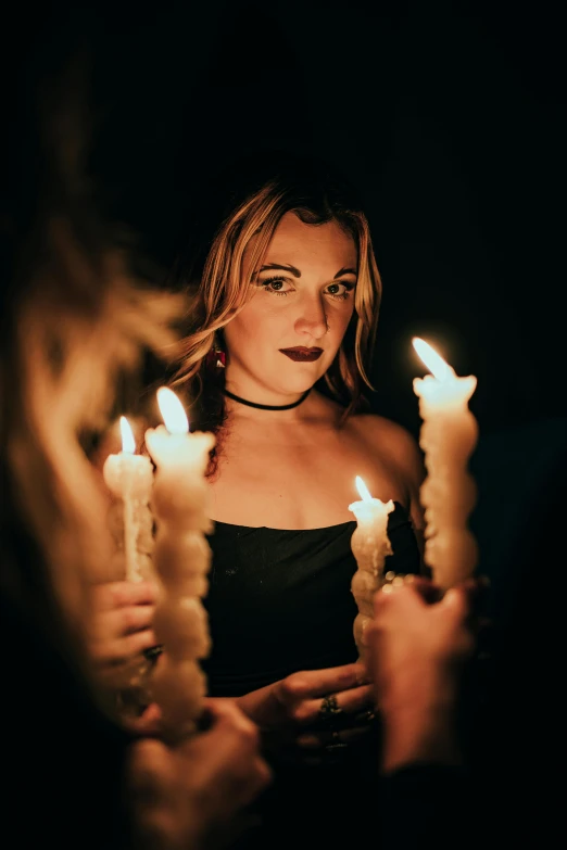 beautiful woman in black dress holding lit candles