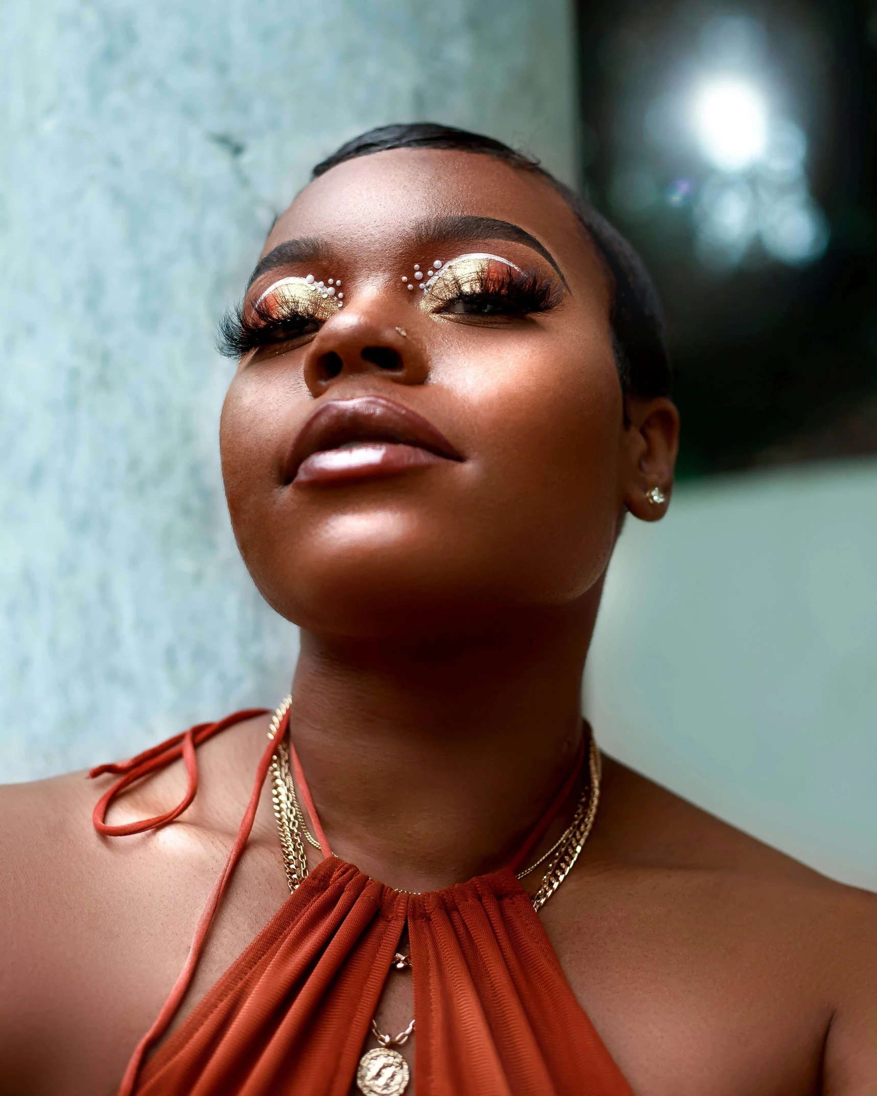 an african woman wearing gold make up with her eyes closed