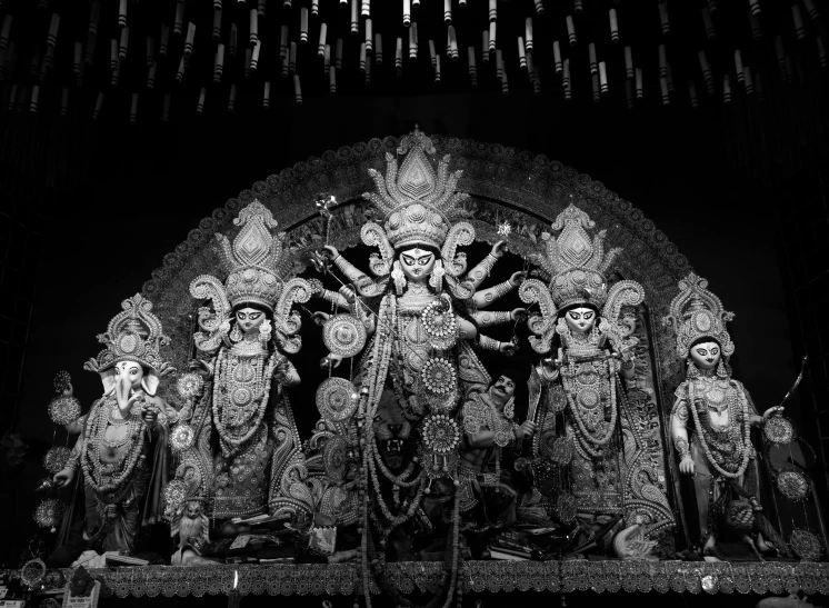 black and white po of the indian god in front of ornate sculpture