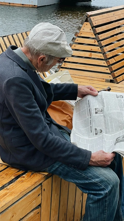 an older man sitting on a bench with paper in his lap