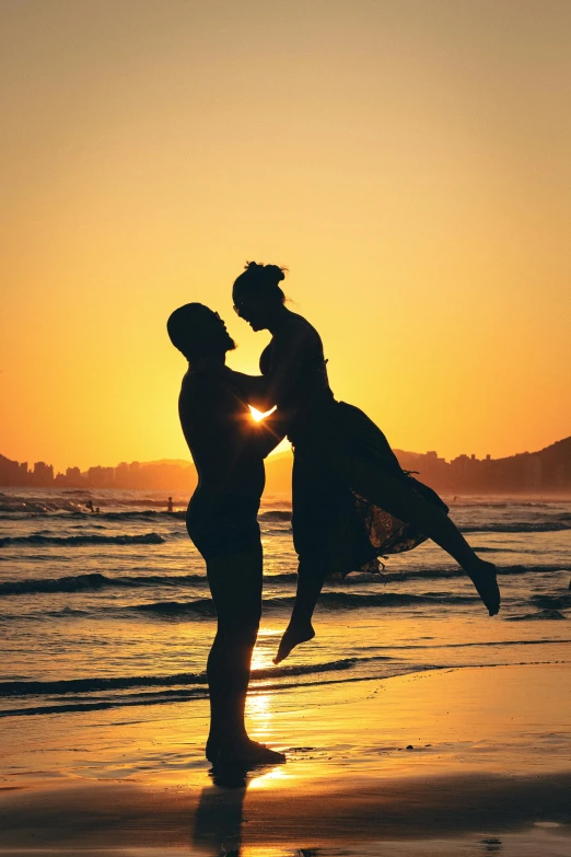 two people in silhouette on the beach as sun sets