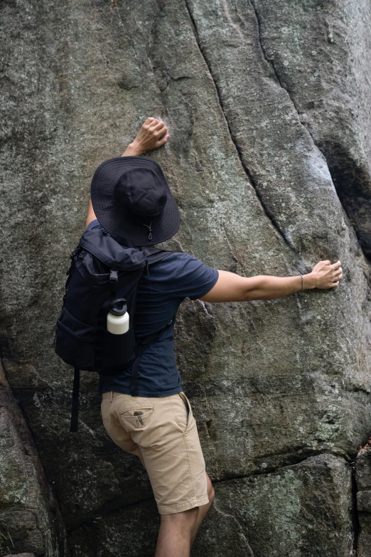 man with a backpack on his back climbing on the side of a rocky cliff