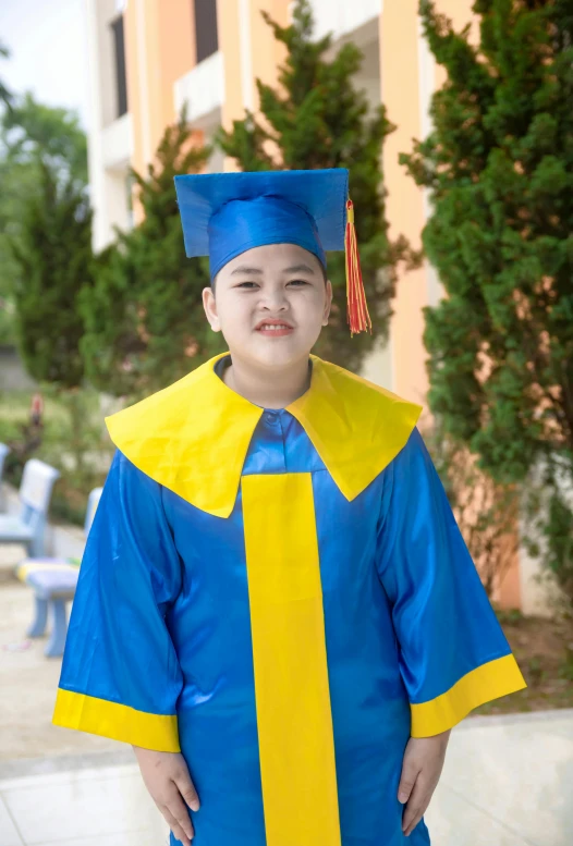 a child dressed in a yellow and blue graduation gown