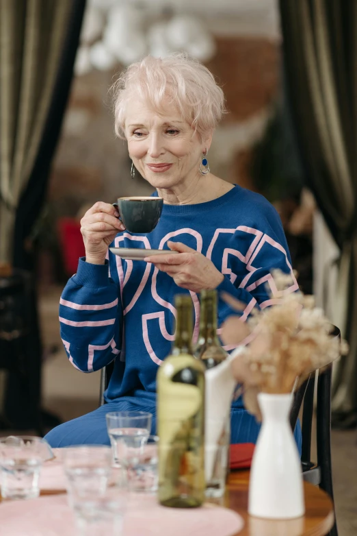 an older woman is drinking from her cup