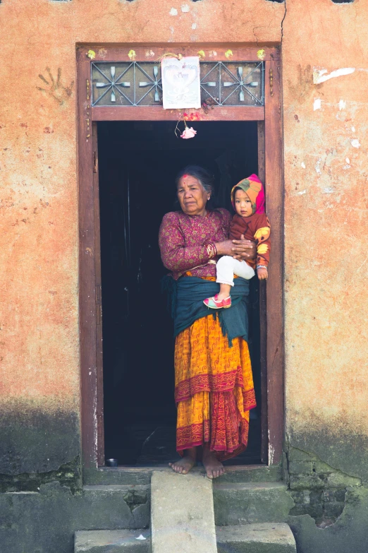 a woman is holding her child as she stands in an open door