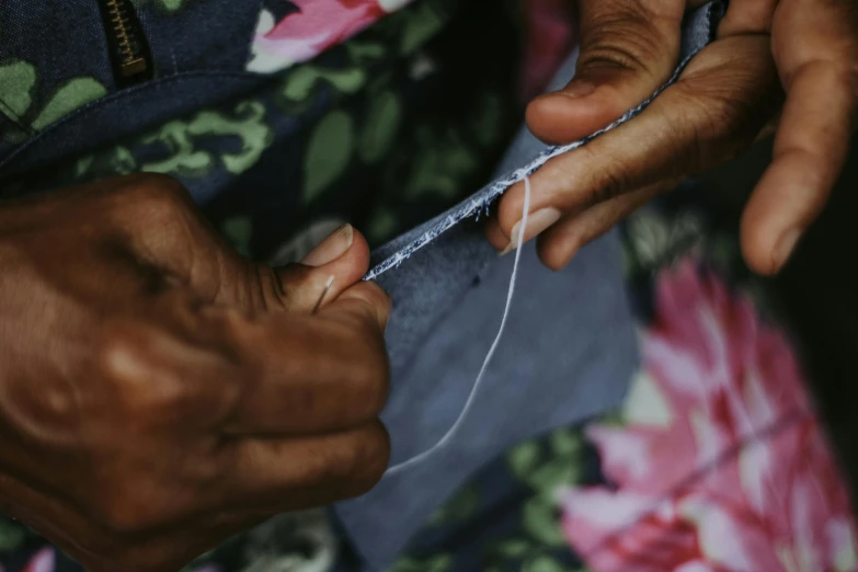 a woman holds some thread and needles to the end of soing