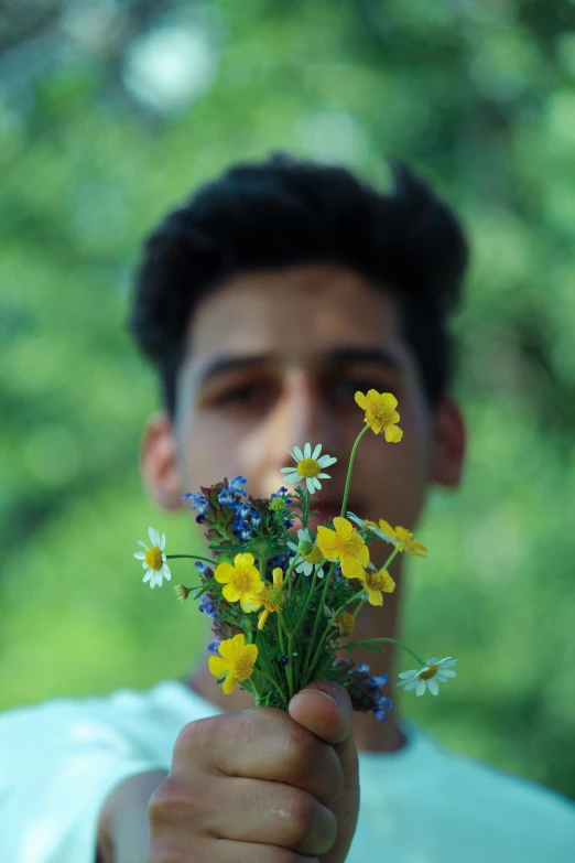 man holding a bouquet of flowers near his face