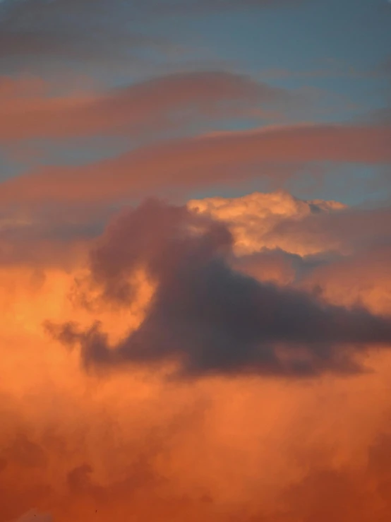 a plane flying across an orange sky with some clouds