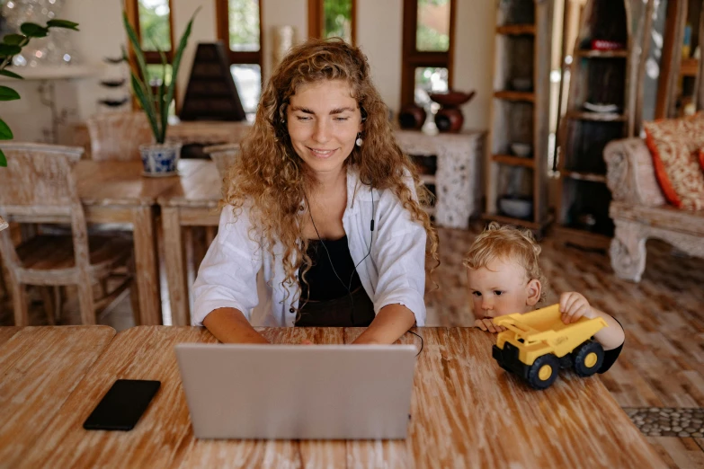 a woman at a table with a child using a laptop