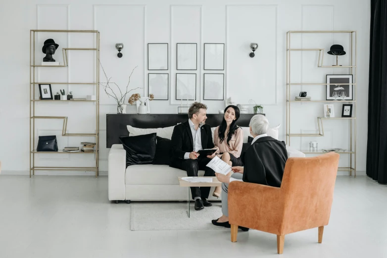 a woman sitting on a couch with her arm around another man who is facing a woman