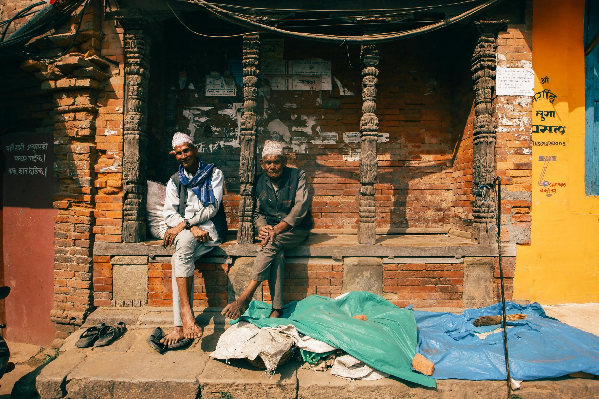 two old men sitting on the step of an orange building