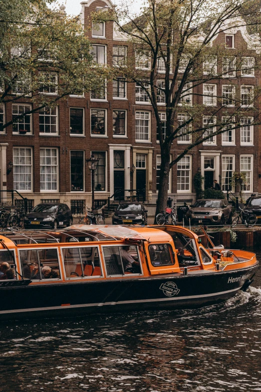 several orange motor boats going down a canal