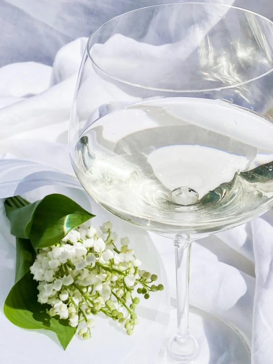 a white plate holding a glass of water and white flowers