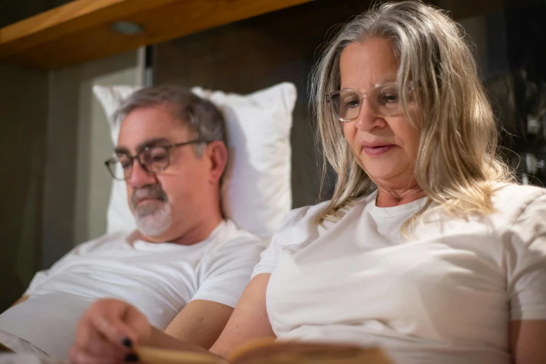 man with glasses and blonde haired woman reading a book