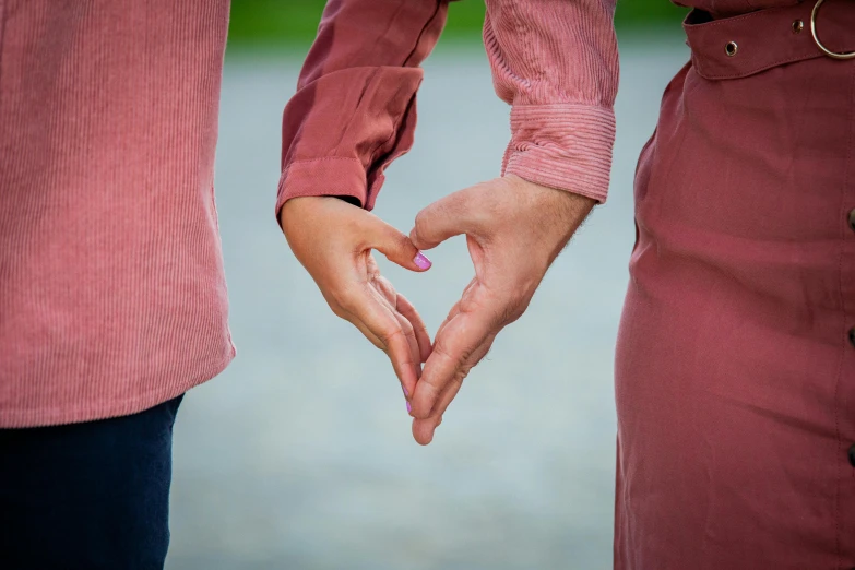 the hands of two people in pink holding each other