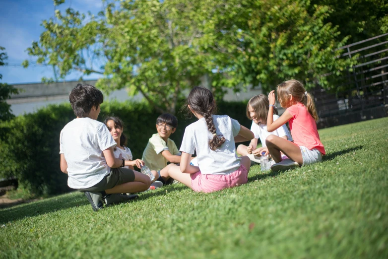 group of children sitting in grass on a sunny day