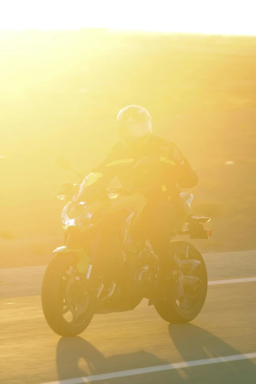 man rides his motorcycle in the sunlight in front of the camera