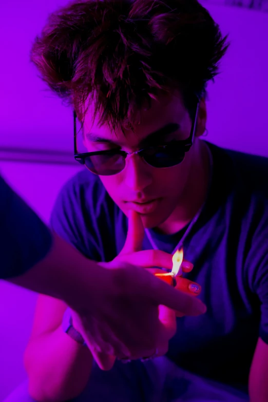 a young man wearing shades holding a lit candle