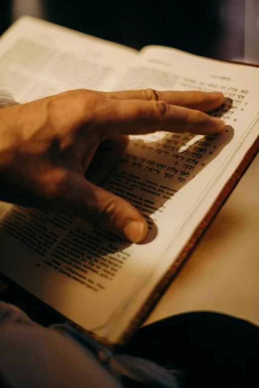 a person with their hand on an open book