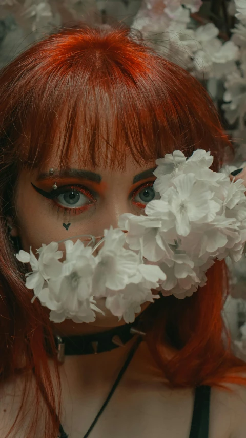 the young woman with a wreath of flowers is wearing a choker and her hair dyed red
