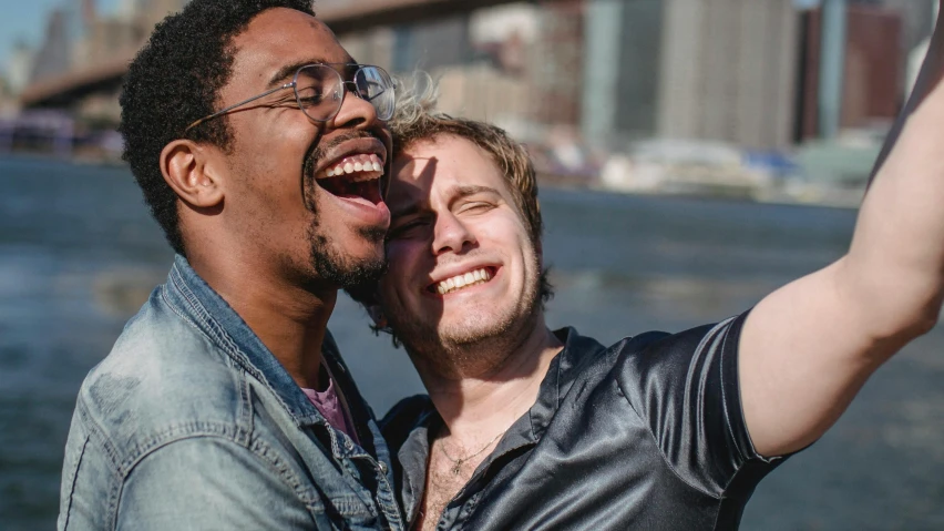 a couple of men are hugging in front of the water