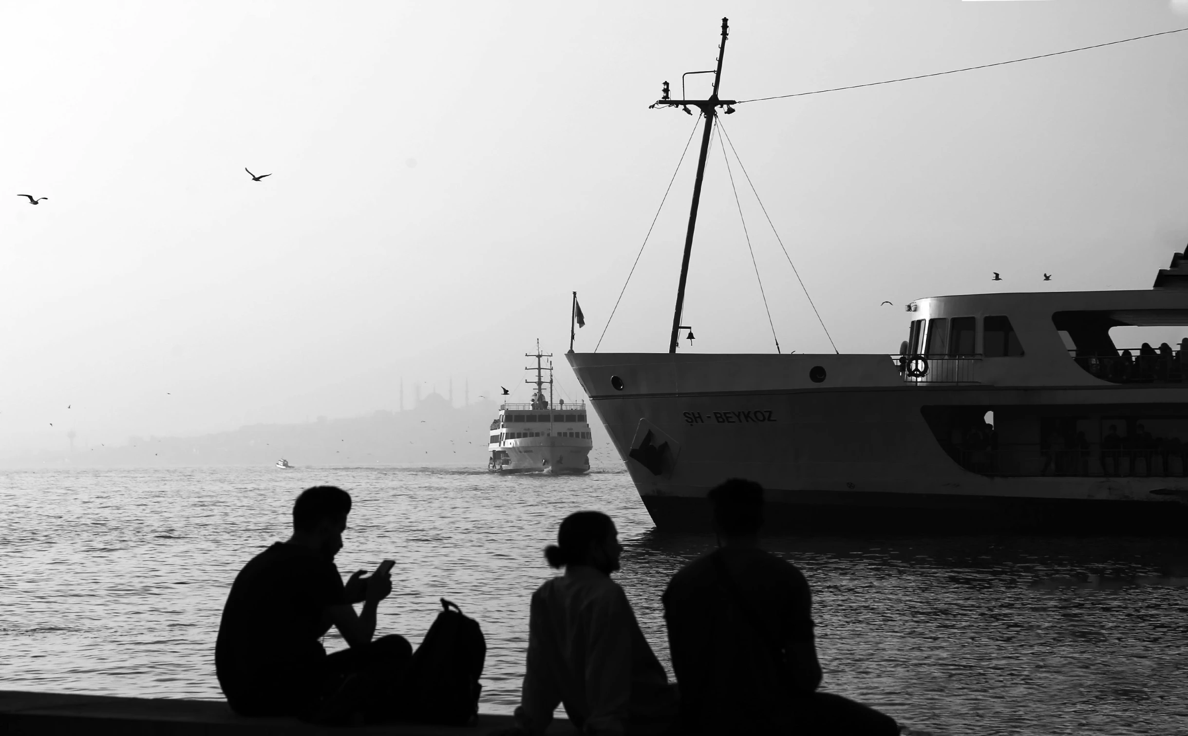 some people sitting on a dock with a boat and bird in the sky