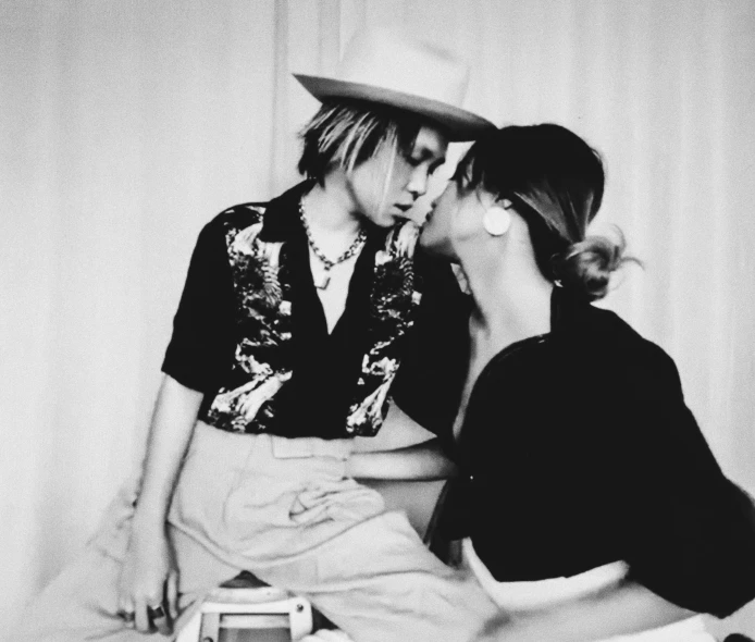 two young women are sitting on the bed together